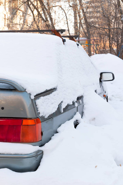 velho carro quebrado abandonado estacionado pela estrada sob uma grande camada de neve em um dia frio de inverno - Foto, Imagem