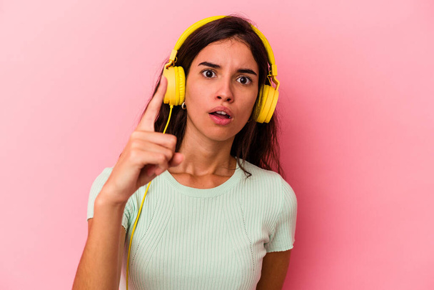 Young caucasian woman listening music isolated on pink background having an idea, inspiration concept. - Φωτογραφία, εικόνα