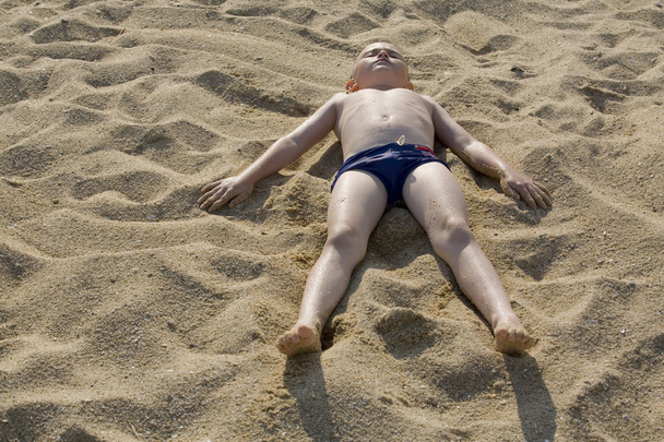 Мальчик лежит на песке
 - Фото, изображение