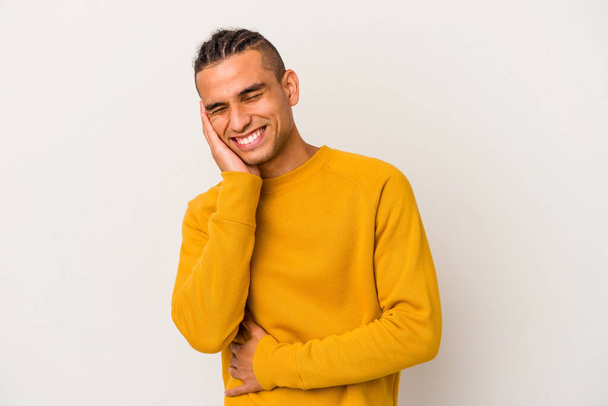 Young venezuelan man isolated on white background laughs happily and has fun keeping hands on stomach. - Photo, Image