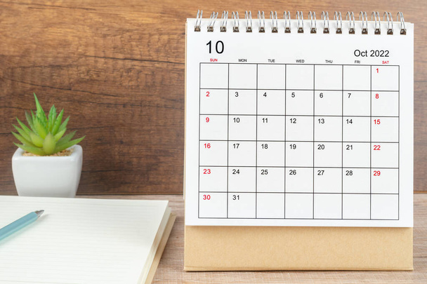 Octubre mes, Calendario de escritorio 2022 para el organizador de la planificación junto con la pluma y el cuaderno sobre la mesa. Concepto de reunión de planificación empresarial - Foto, imagen