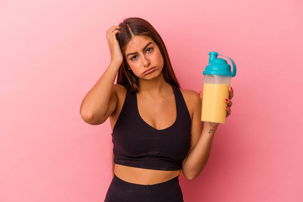 Young caucasian woman holding a protein shake isolated on yellow background being shocked, she has remembered important meeting. - Photo, Image