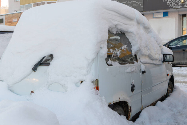 старий білий покинутий зламаний іржавий автомобіль, припаркований біля дороги під великим шаром снігу в холодний зимовий день
 - Фото, зображення