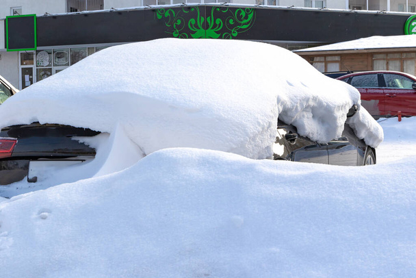 冬の新しい黒い放棄された車明るい晴れた霜の日に雪の大規模な層の下に駐車 - 写真・画像