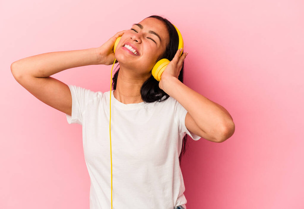 Junge Venezolanerin hört isoliert Musik auf rosa Hintergrund - Foto, Bild