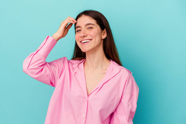 Young caucasian woman isolated on blue background joyful laughing a lot. Happiness concept. - Foto, afbeelding