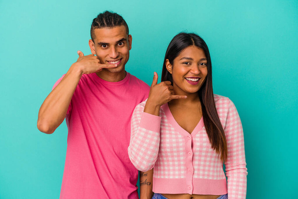 Young latin couple isolated on blue background showing a mobile phone call gesture with fingers. - Photo, Image