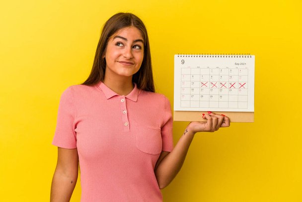 黄色の背景に隔絶されたカレンダーを持つ若い白人女性目標と目的を達成することを夢見て - 写真・画像