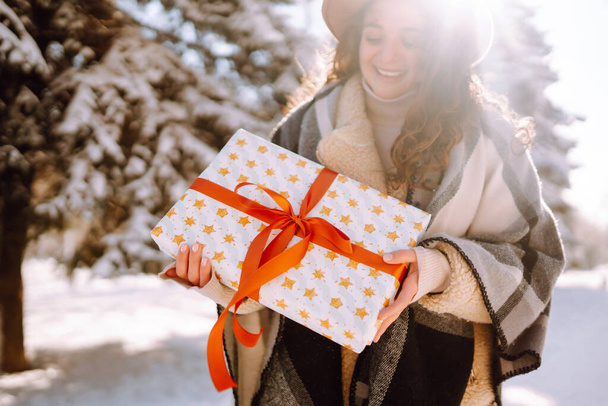 Christmas or New Year gift box in the female hands. Young Woman holding presents  in the snow park. Winter holidays. - Фото, изображение