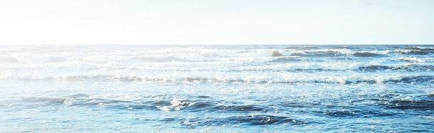 Вид з Балтійського моря на захід сонця. Чисте блакитне вечірнє небо, хвилі і водяні бризки. Ідилічний морський мис. Латвія - Фото, зображення