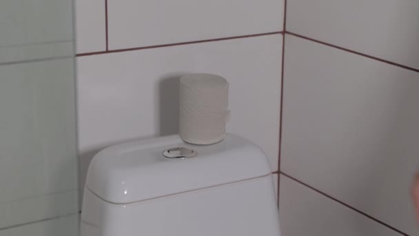 de hand drukt op de knop om het toilet door te spoelen, de knop op de spoeltank, close-up - Video