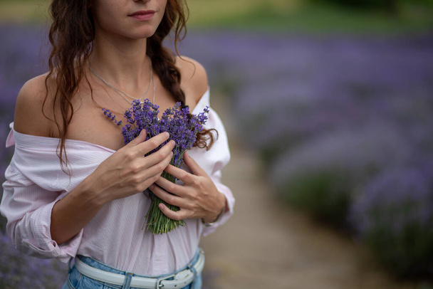 Closeup happy beautiful girl enjoying lavender field with bouquet of flowers - Fotó, kép