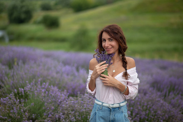  happy beautiful girl enjoying lavender field with bouquet of flowers - Photo, Image