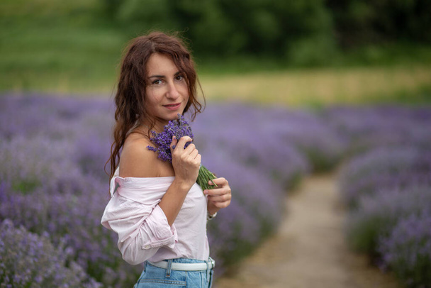 Closeup happy beautiful girl enjoying lavender field with bouquet of flowers - Zdjęcie, obraz