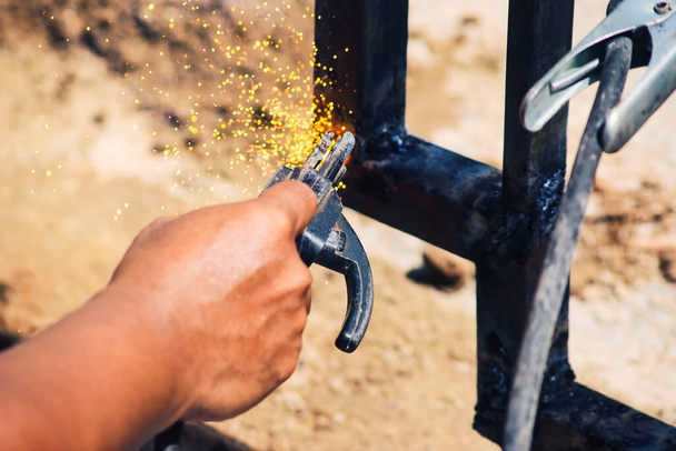 Bir işçi eldiven takmadan demir kaynaklıyor. Hafif kaynak çalışması. - Fotoğraf, Görsel