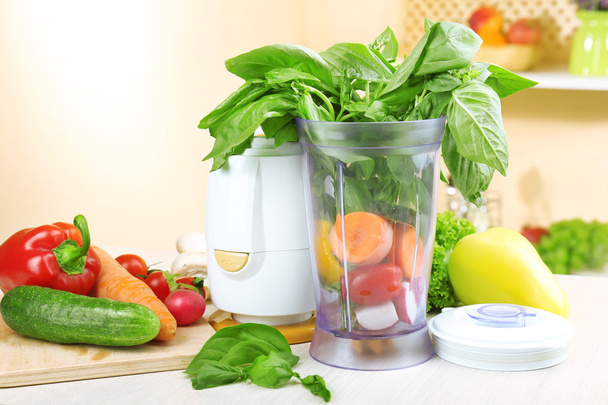 Blender with fresh vegetables on kitchen table - Photo, image