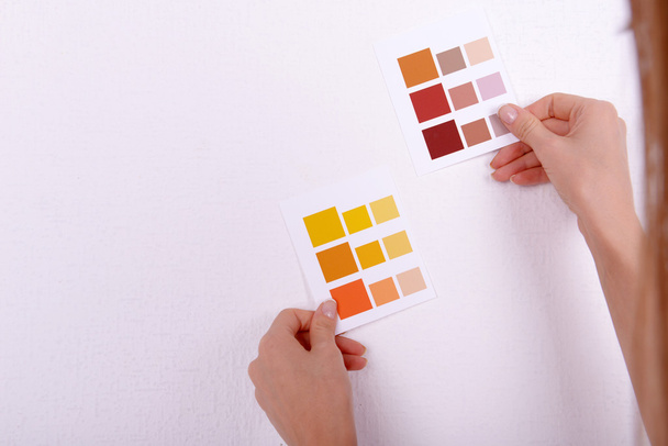 γυναίκα επιλέγοντας χρώμα για τον τοίχο από τα δείγματα στο δωμάτιο - Φωτογραφία, εικόνα