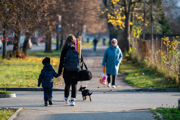 Riga, Latvia, November 2, 2021: a woman with a child and a dog on a sidewalk in an autumn city, rear view - Foto, Imagem