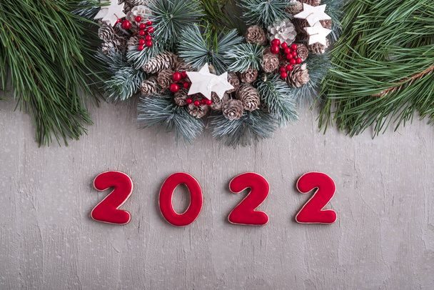 Red number 2022 from gingerbread and christmas wreath. Good New Year spirit. Light gray wall on background. - Fotografie, Obrázek