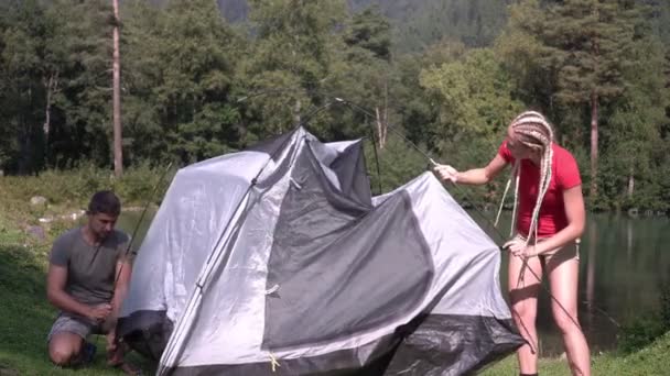 Gelukkige paar wandelaars op een wandeling zette een tent bij het meer in het bos - Video