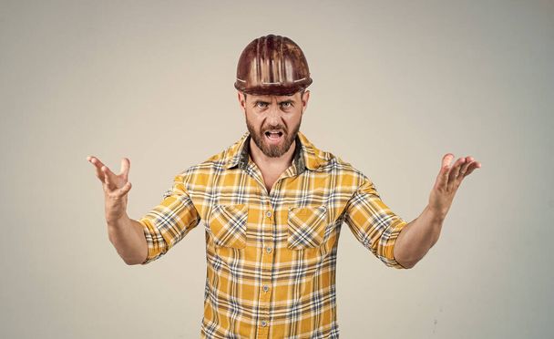 mature builder in shirt. unshaven man on construction site. handsome building worker in hard hat. labor day. angry guy wear safety helmet solve problem. engineer on work. male lifestyle - Foto, Imagen