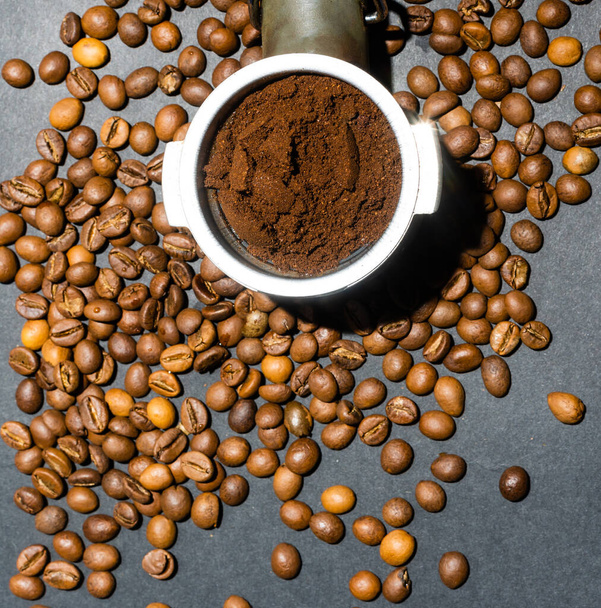 Ground coffee in a horn among aromatic beans. Home coffee making concept. Horizontal orientation. Top view. Close-up. - Photo, Image