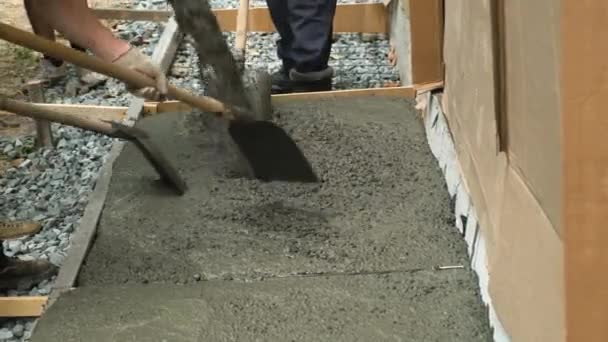 Os trabalhadores estão derramando concreto na cofragem da casa. Trabalhadores ancinho e nivelar o concreto na cofragem da casa. - Filmagem, Vídeo