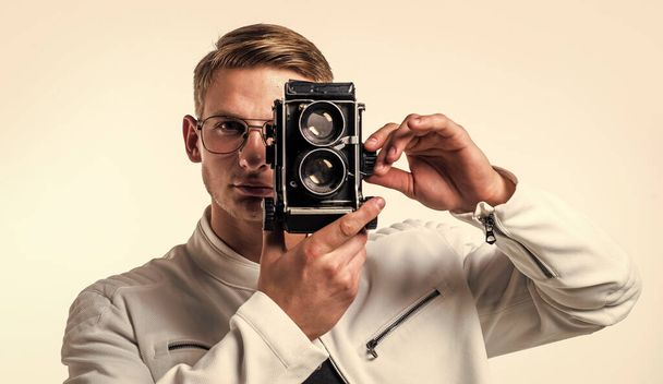 Camera that puts a world of possibilities at your fingertips literally. Young photographer isolated on white. Handsome man take photo with vintage camera. Photography equipment. Shooting session - Foto, imagen