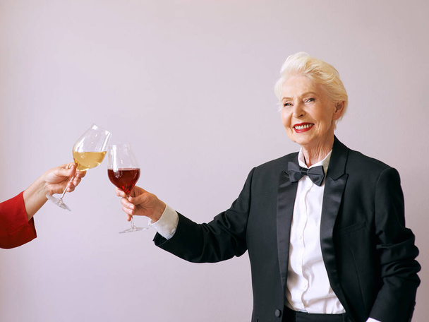 elegante mujer sommelier senior en esmoquin con copa o vino tinto en la fiesta. Bebida, maduro, estilo, concepto de amistad  - Foto, Imagen