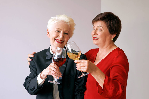 Twee mooie, stijlvolle oudere vrouwen die wijn drinken. Plezier, feestje, stijl, feestconcept - Foto, afbeelding