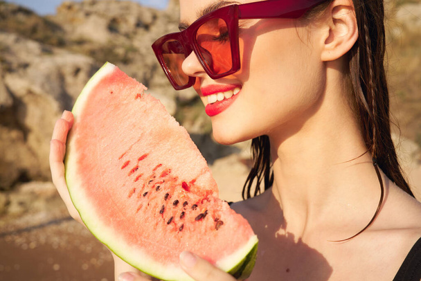 cheerful woman in sunglasses and watermelon nature rocks - Foto, Imagen