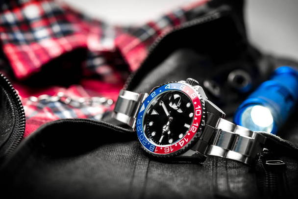 Крупный план роскошные наручные часы для мужчин с черным циферблатом сине-красный безель и браслет из нержавеющей стали. - Фото, изображение
