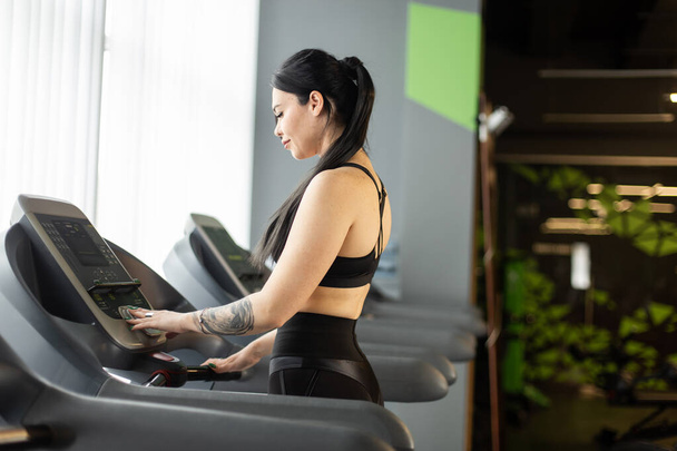 Jeune femme de fitness faisant de l'exercice cardio sur un tapis roulant dans une salle de gym moderne. Mode de vie sain, concept sportif - Photo, image