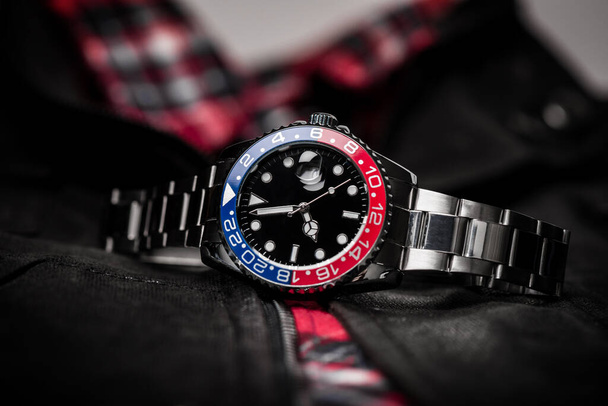 Nahaufnahme Luxus-Armbanduhr für Männer mit schwarzem Zifferblatt blau-rote Lünette und Edelstahlarmband. - Foto, Bild