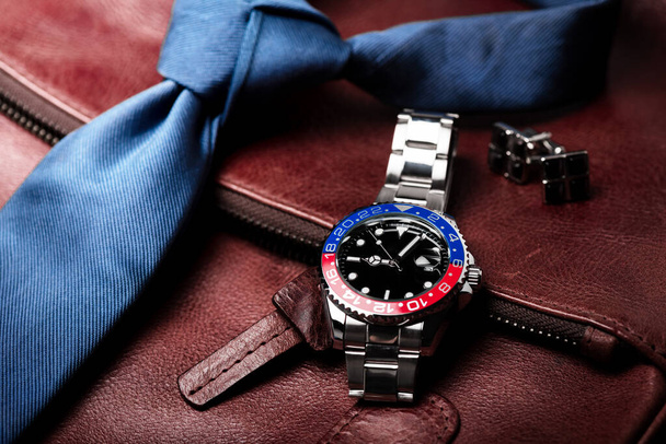 closeup relógio de pulso de luxo para homens com mostrador preto moldura azul-vermelho e pulseira de aço inoxidável. - Foto, Imagem