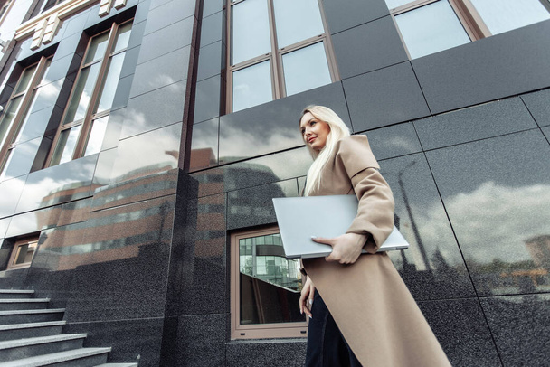 Tyylikäs blondi liiketoiminnan nainen kannettavan tietokoneen trench takki kaupunkialueella - Valokuva, kuva