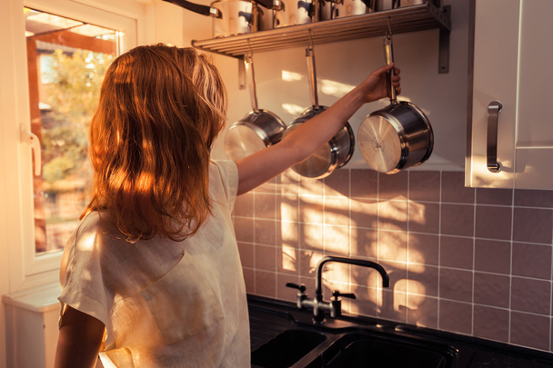 Young woman in kitchen cooking with saucepan - Valokuva, kuva