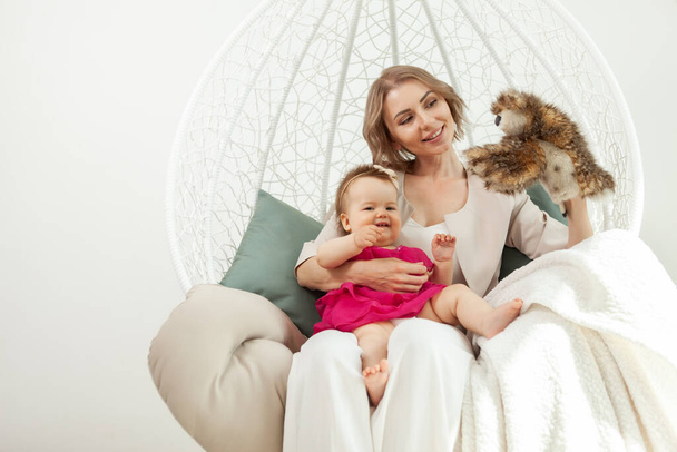 Happy loving family. Mother and little daughter in living room. Cute mom and lovely baby have fun and play with owl puppet - Foto, Imagen