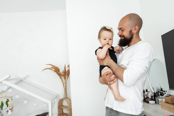 Caring father man holding little daughter in his arms in bedroom - Photo, Image