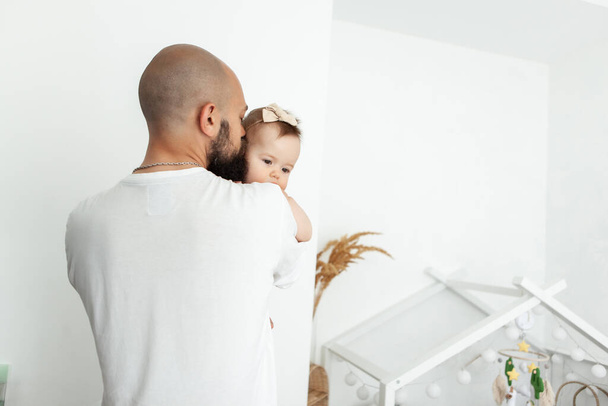 Caring father hugs his little daughter in the room. Love and care, happy family - 写真・画像