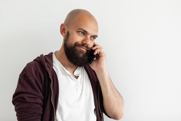 Bearded bald handsome man talking on the phone on white background - Foto, imagen