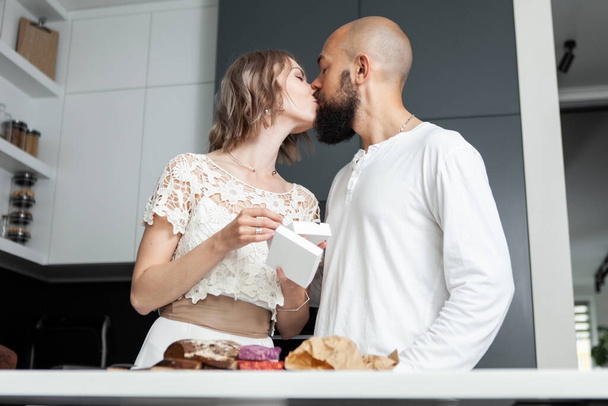 妻は彼女の夫にキスをします,彼は台所で彼女を与えた贈り物のおかげで.愛、ロマンチックな概念 - 写真・画像