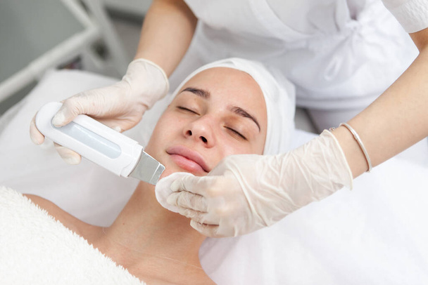 Beautiful woman receiving ultrasonic cavitation facial peeling. Ultrasonic skin cleansing procedure. Cosmetic procedures. Cosmetology. Beauty salon. Skin care. - Photo, image