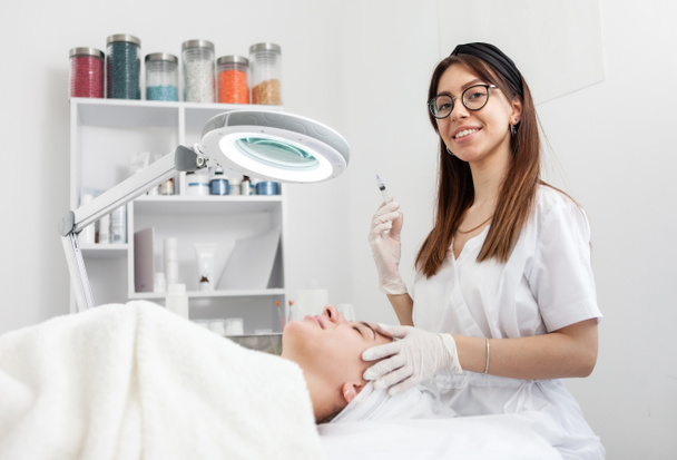 El cosmetólogo hace las inyecciones para la arruga antiarrugas de la mujer hermosa. Cosmetología femenina en salón de belleza - Foto, imagen