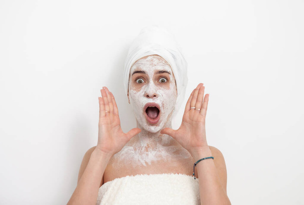 Shocked beautiful woman with facial mask on white background. Skin care concept - Photo, Image