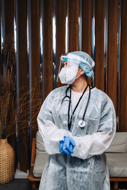 oung woman nurse worker in medical protective mask, gloves and protective wear standing in hospital hall - Photo, Image