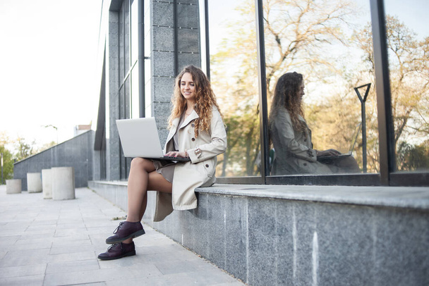 Aranyos mosolygós nő laptoppal ül a háttérben az üzleti központ - Fotó, kép