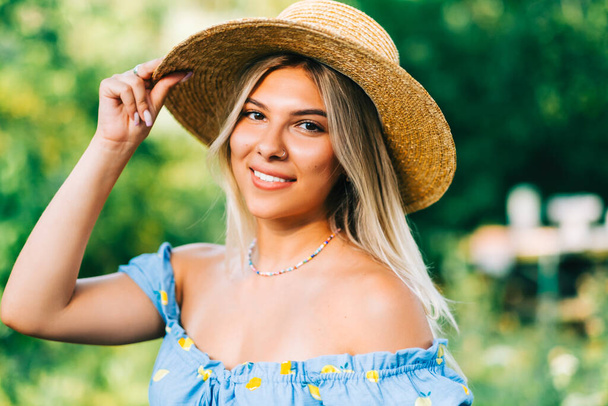 Portrait of attractive young woman in straw hat outdoors in summer sunny day. - Foto, imagen