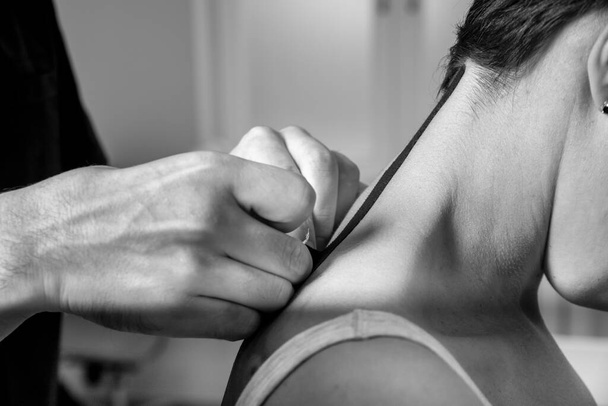 Black and white photo Osteopathic doctor glues elastic tapes to the neck for treatment. Medicine. High quality photo - Foto, immagini