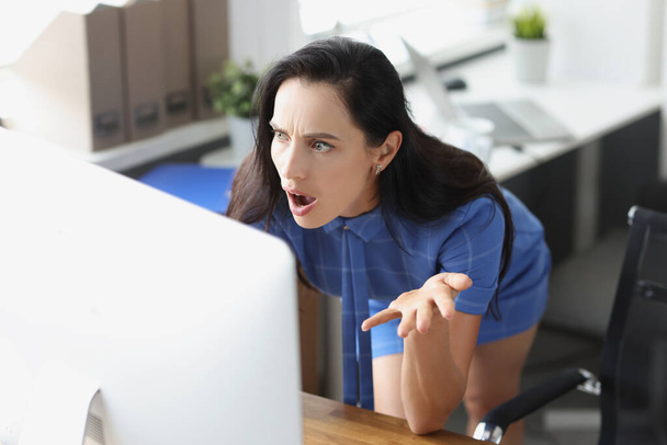 Удивлённая деловая женщина смотрит на экран компьютера в офисе - Фото, изображение